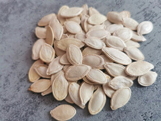Closeup of white pumpkin seeds on a gray backround. Healthy fats, magnesium and zinc