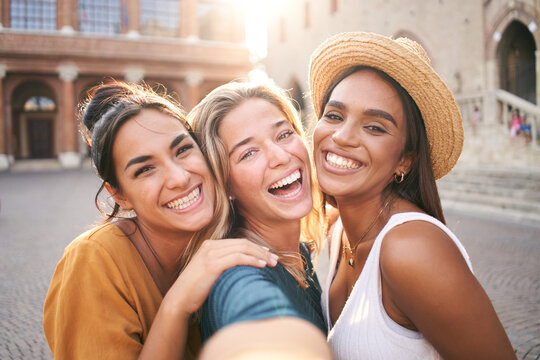 Three young smiling hipster women in summer clothes. Girls taking selfie self portrait photos on smartphone.Models posing in the street.Female showing positive face emotions
