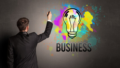 businessman drawing colorful light bulb