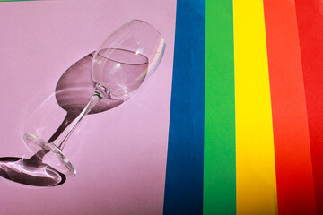 Top view of colored paper backgrounds laid out in the LGBT flag of pride with a glass. LGBT flag...