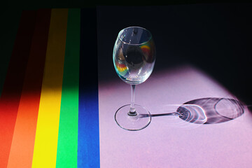 Top view of colored paper backgrounds laid out in the LGBT flag of pride with a glass. LGBT flag colors. Celebration concept.