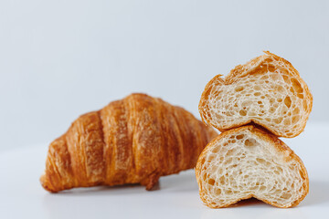 Two halves of a croissant on a background of a whole croissant on a white background