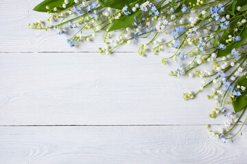 Spring lilies of the valley, forget me not flowers on a white wooden background, space for greeting text