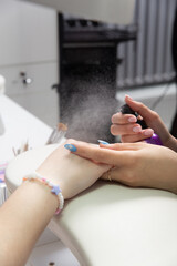 Obraz na płótnie Canvas Manicurist sprays antiseptic on the nails before treating old acrylic nails.