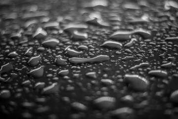 Rainwater splash and bubbles on dark black surface