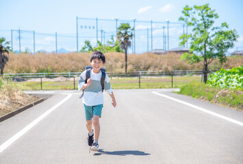 走って学校に登校する小学生の男の子