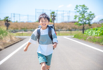 走って学校に登校する小学生の男の子