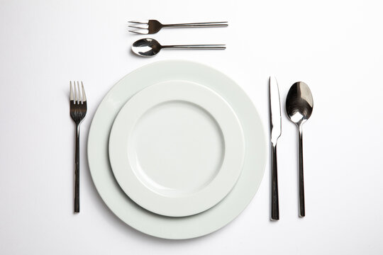 Empty White Plate With Spoon, Knife And Fork On White Background