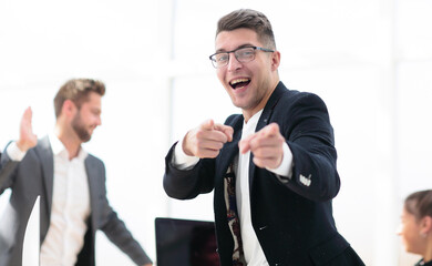 Naklejka premium cheerful business man standing in the office and pointing at you.