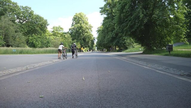 Time lapse. People walking and biking on a road in the park.