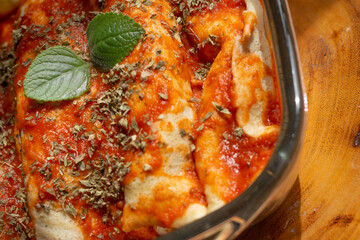 delicious pancakes topped with tomato sauce and oregano on the wooden table