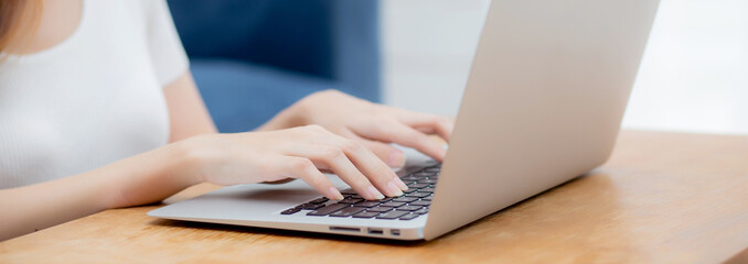 Closeup hand of woman typing keyboard on laptop computer on desk at home, business woman working to internet online, freelance girl using notebook on table, communication and lifestyle concept.
