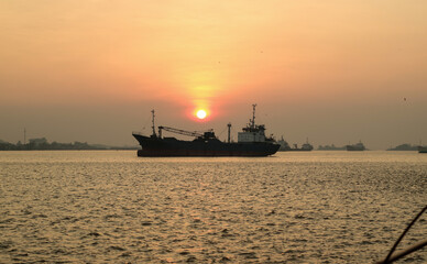 Obraz premium sunset view from the bank of the kapuas river. silhouette of a large ship in the middle of the river.
