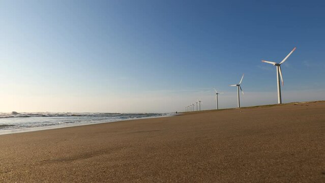 青空と海岸の風力発電の風車。茨城県神栖市須田浜海岸の波崎ウインドファーム。