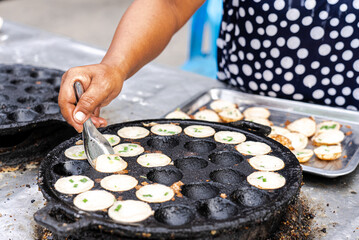 Thai Woman Making Thai Coconut Puddings or Kanom Krok With Topping in Morning - obrazy, fototapety, plakaty