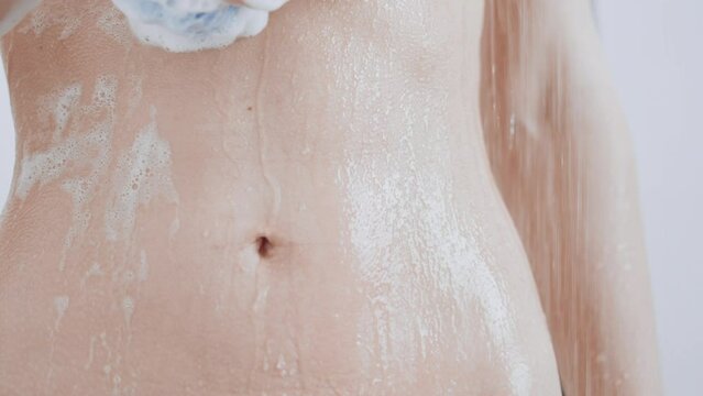 female with athletic body take a bath foam flows down the slim stomach hygiene and skin care concept