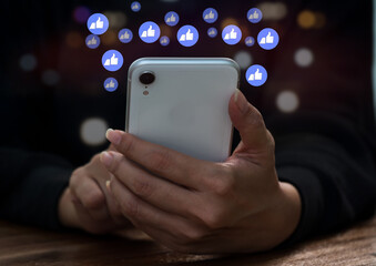a woman typing on her smartphone to interact with others via emoji and text online idea with like, message, email, comment, and star notification buttons atop smartphone screen