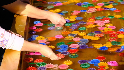 Hands of people floating colorful candle floating on water for pray at the temple.