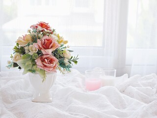 Artificial pink rose flowers bouquet in vase on white embroidered cloth copy space text or writing pretty background or wallpaper mother's day still life ,women's day festive background spring flora