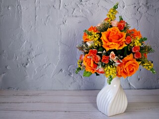 Orange roses artificial flowers bouquet in vase on table, copy space for text or writing ,texture...