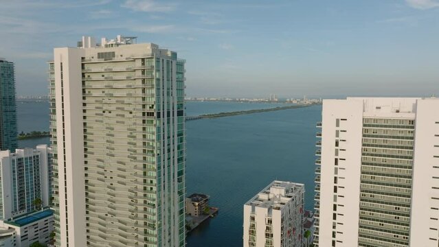 Forwards fly above tall apartment buildings on waterfront. Busy road and bridge leading to Miami Beach. Miami, USA