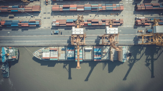 Aerial view of Logistics and transportation of Container Cargo ship and Cargo plane with working crane bridge in shipyard, logistic import export and transport industry background