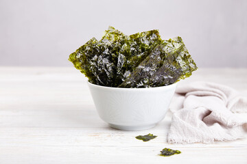 Crispy nori seaweed on bowl on grey background. Traditional Japanese dry seaweed sheets. Healthy snack.  - obrazy, fototapety, plakaty