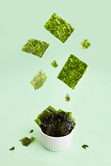 Flying crispy nori seaweed. Healthy snack. Traditional Japanese dry seaweed sheets. Creative concept, levitation. - obrazy, fototapety, plakaty