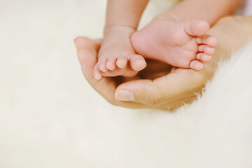Obraz na płótnie Canvas Close Up newborn infant Baby feet in mother hands. Baby's feet on female Shaped hands Mom and her Child. Beautiful conceptual image of Maternity
