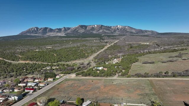 Aerial Monticello Utah rural neighborhood fast pull. Settled in July 1887 by pioneers from The Church of Jesus Christ of Latter-day Saints. Farming, ranching, and uranium mining. Mountain valley.