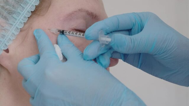 Woman getting anti-aging injection to the face, close up. Cosmetic surgery facial in beauty clinic. Female patient on procedure for pull up face contour.