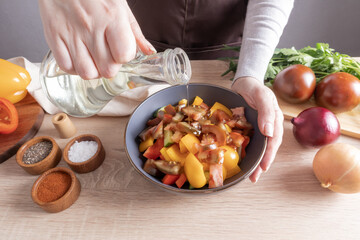a young girl's hand pours oil from a bottle over sliced lettuce into slices in a bowl. cooking at home.