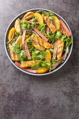 Grilled Chicken salad with rhubarb, oranges, onions and lettuce closeup on the wooden board on the table. Vertical top view from above