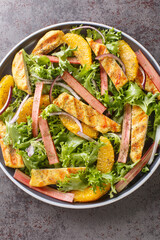 Rhubarb and chicken salad with oranges, onions and lettuce closeup on the wooden board on the table. Vertical top view from above