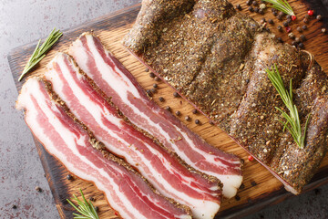 Stripy cured pork side bacon pancetta smoked on wood chip closeup on the wooden board on the table....