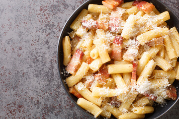 Pasta alla gricia plate of delicious italian pasta with guanciale and pecorino, typical italian and roman food closeup in the plate on the table. Horizontal top view from above