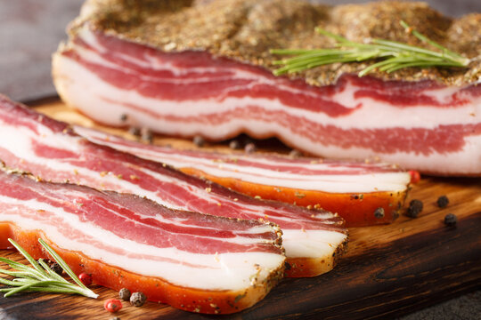 Stripy cured pork side bacon pancetta smoked on wood chip closeup on the wooden board on the table. Horizontal