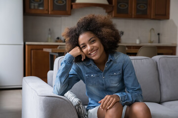 Portrait happy smiling millennial Afro American lady homeowner renter tenant sitting relaxing on...