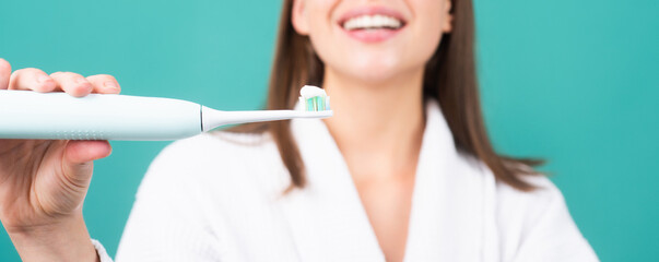 Closeup on happy young woman brushing teeth. Toothbrush with toothpaste. Electric toothbrush....