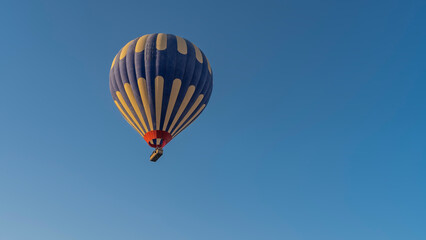 Naklejka premium A bright blue-yellow balloon in a clear azure sky. Close-up. Copy Space