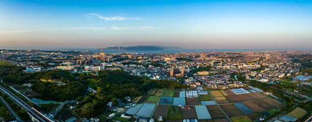 Sunrise panorama with rice fields, sprawling Japanese town, and bridge to island in background © Osaze