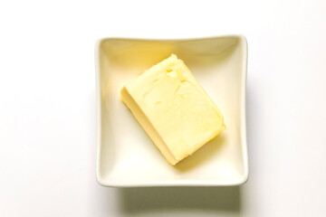 Butter pieces in bowl isolated on white background, top view.
