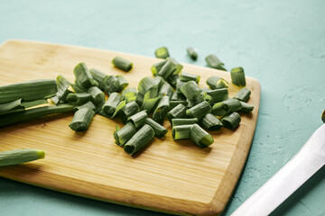 sliced green onions on a wooden chopping board next to a knife