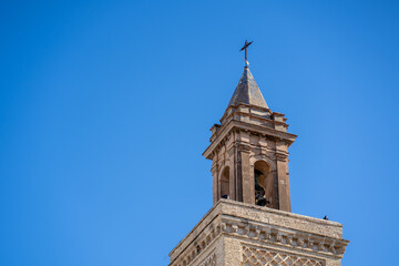 Fototapeta na wymiar The stone tower of the church in the old town of Spain is a cross with a blue sky