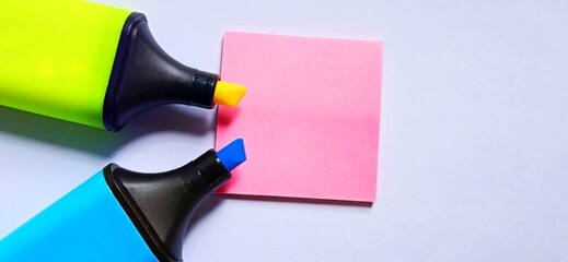 Isolated blue and yellow markers and isolated pink square note on the gray white space background.