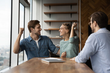 Happy excited couple feeling joy in realtor office, celebrating getting mortgage, renting or buying...