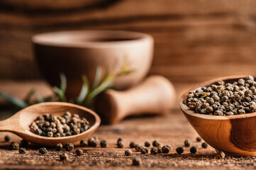 Black pepper in wood bowl on wooden table. Spices on desk. Organic spice dry peppercorn.