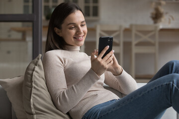 Happy dreamy beautiful millennial girl chatting online in deep thoughts, using dating websites...