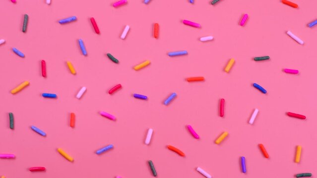 A rotation background of sprinkles for sweets on a pink background.The concept of celebrating a birthday, party or other holidays.fashionable,sweet background