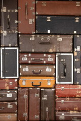 Wall of vintage antique stylish luggage cases. Old fashioned travel bags background. Texture from retro shabby leather stacked suitcases. Airport, journey, trip, adventure concept. Vertical shot